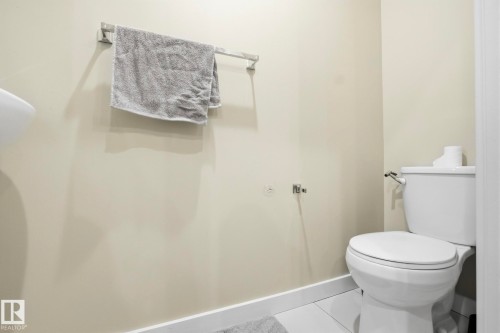 White ceramic toilet with polished chrome hardware - 30 6075 Schonsee Way, Edmonton, AB - Indoor Photo Showing Bathroom