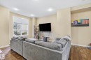 Living area featuring wood-finish flooring, a large window with white trim, recessed lighting, and neutral wall tones - 30 6075 Schonsee Way, Edmonton, AB  - Indoor 