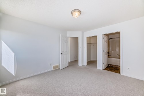 Carpeted room featuring a ceiling-mounted light fixture, multiple panel doors, and a built-in closet - 2339 28B Ave Avenue, Edmonton, AB - Indoor