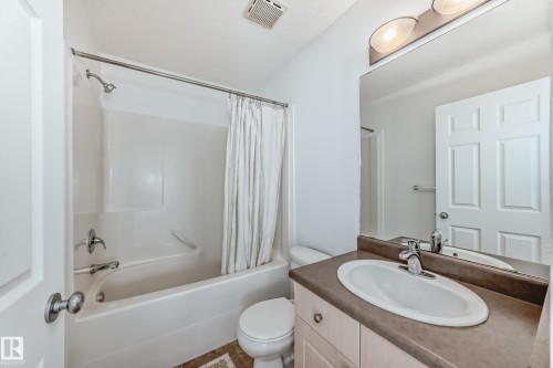 Bathroom featuring a white bathtub and shower combination, a vanity with a light-colored countertop, and a large wall-mounted mirror - 2339 28B Ave Avenue, Edmonton, AB - Indoor Photo Showing Bathroom