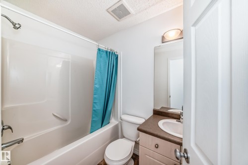 Bathroom featuring a white tub-shower combination, a vanity with a dark countertop and integrated sink, a large wall-mounted mirror, and a wall-mounted light fixture - 2339 28B Ave Avenue, Edmonton, AB - Indoor Photo Showing Bathroom