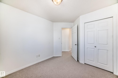 Neutral wall paint with carpet flooring, featuring a flush mount ceiling light and bi-fold closet doors - 2339 28B Ave Avenue, Edmonton, AB - Indoor Photo Showing Other Room