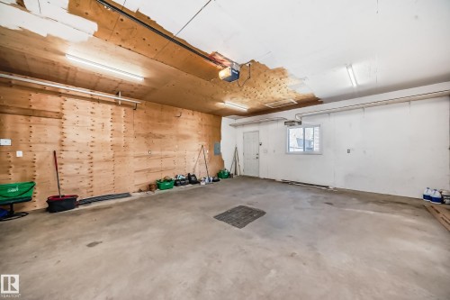 Spacious garage featuring a concrete floor, plywood paneling, overhead lighting, and an automatic garage door opener - 2339 28B Ave Avenue, Edmonton, AB - Indoor Photo Showing Garage