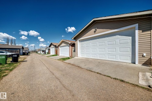 Dedicated rear-access garage with a paneled white door, beige vinyl siding, and concrete driveway - 2339 28B Ave Avenue, Edmonton, AB - Outdoor