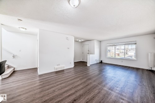 Open-concept living area featuring wood-finish flooring, white painted walls, and overhead flush mount lighting - 2339 28B Ave Avenue, Edmonton, AB - Indoor