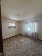 Spacious room featuring patterned carpeting, white walls, and a textured ceiling - 