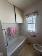 Bathroom featuring a built-in bathtub with subway tile surround, mosaic accent tiles, and two wall-mounted storage cabinets - 