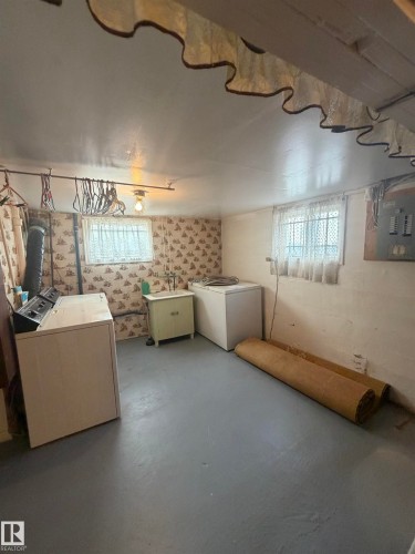 Spacious utility area featuring a painted concrete floor, two windows providing natural light, and a dedicated laundry appliance zone - 9630 106 Avenue, Edmonton, AB - Indoor