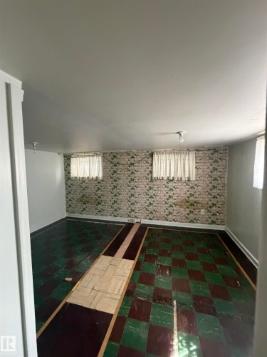 Room featuring patterned floor tiles, white baseboards, and a partial accent wall with a brick-like pattern - 9630 106 Avenue, Edmonton, AB - Indoor Photo Showing Other Room