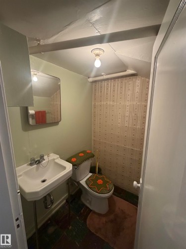 Compact bathroom featuring a wall-mounted sink, toilet, and patterned wallpaper - 9630 106 Avenue, Edmonton, AB - Indoor Photo Showing Bathroom