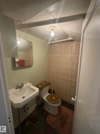 Compact bathroom featuring a wall-mounted sink, toilet, and patterned wallpaper - 