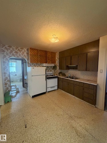 Kitchen featuring wood-finish cabinetry, laminate countertops, and a white appliance suite - 9630 106 Avenue, Edmonton, AB - Indoor Photo Showing Kitchen
