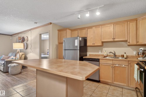 Functional kitchen featuring light wood cabinetry, a stainless steel refrigerator, and a coordinating dishwasher - 110 2903 Rabbit Hill Road, Edmonton, AB - Indoor Photo Showing Kitchen With Double Sink