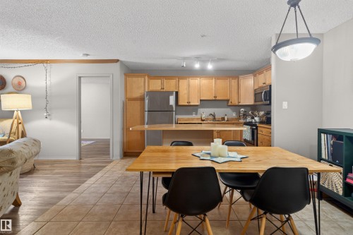 Kitchen featuring light wood cabinetry, stainless steel appliances, and a breakfast bar - 110 2903 Rabbit Hill Road, Edmonton, AB - Indoor