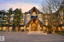 Multi-story building featuring a stone and siding exterior with prominent gabled rooflines, large windows, and individual balconies - 110 2903 Rabbit Hill Road, Edmonton, AB  - Outdoor With Facade 