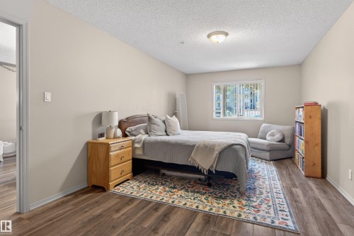 Bedroom with wood-finish flooring, neutral wall tones, and a window providing natural light - 110 2903 Rabbit Hill Road, Edmonton, AB - Indoor Photo Showing Bedroom