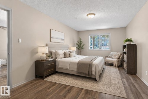 Spacious room featuring wood-finish flooring, a large window with vertical blinds, and neutral wall paint - 110 2903 Rabbit Hill Road, Edmonton, AB - Indoor Photo Showing Bedroom