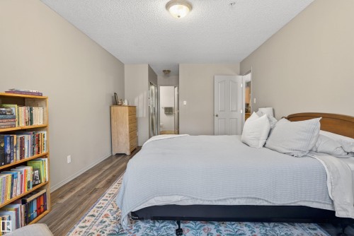 Spacious room featuring wood-finish flooring, neutral wall tones, and an overhead flush-mount light fixture - 110 2903 Rabbit Hill Road, Edmonton, AB - Indoor Photo Showing Bedroom