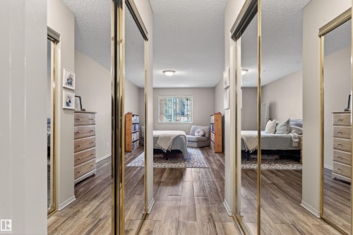 Hallway with mirrored closet doors and wood-finish flooring - 110 2903 Rabbit Hill Road, Edmonton, AB - Indoor Photo Showing Other Room