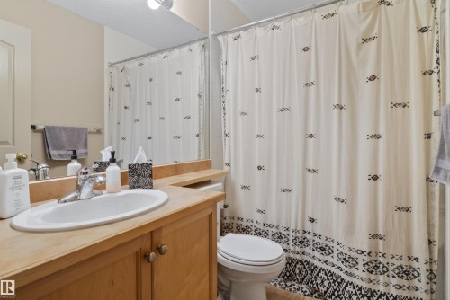 Bathroom featuring a single vanity with wood cabinetry and an integrated sink, a large wall mirror, and overhead lighting - 110 2903 Rabbit Hill Road, Edmonton, AB - Indoor Photo Showing Bathroom