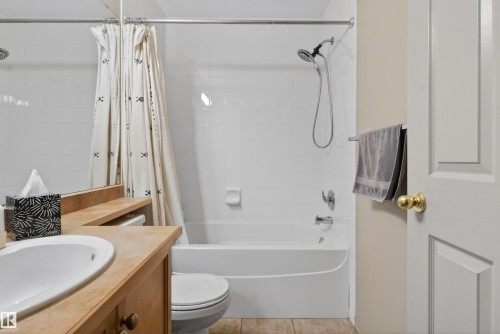 Bathroom featuring a white tub with integrated shower, chrome fixtures, and white tiled surround - 110 2903 Rabbit Hill Road, Edmonton, AB - Indoor Photo Showing Bathroom