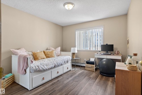 Spacious room featuring wood-finish flooring and a large window with vertical blinds - 110 2903 Rabbit Hill Road, Edmonton, AB - Indoor Photo Showing Bedroom