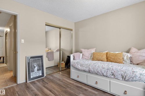 Bedroom featuring wood-finish flooring, neutral wall tones, and mirrored closet doors - 110 2903 Rabbit Hill Road, Edmonton, AB - Indoor Photo Showing Bedroom