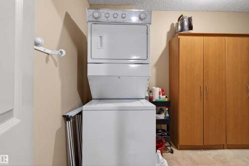 Dedicated utility space featuring a stacked washer and dryer unit - 110 2903 Rabbit Hill Road, Edmonton, AB - Indoor Photo Showing Laundry Room