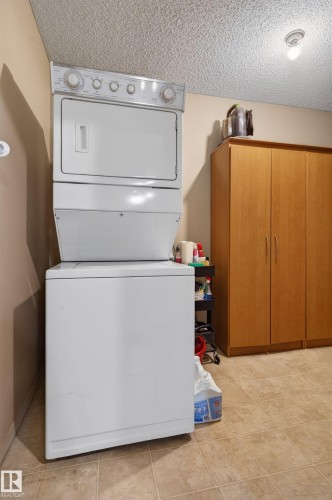 Dedicated laundry area featuring a stacked washer and dryer unit - 110 2903 Rabbit Hill Road, Edmonton, AB - Indoor Photo Showing Laundry Room