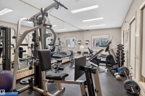 Fitness room with mirrored wall, multiple cardio machines, weight rack, strength training equipment, and recessed lighting - 110 2903 Rabbit Hill Road, Edmonton, AB - Indoor Photo Showing Gym Room