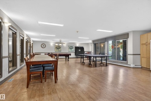 Spacious recreation room featuring wood-finish flooring, recessed lighting, and large windows - 110 2903 Rabbit Hill Road, Edmonton, AB - Indoor