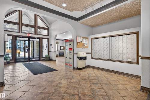 Spacious entry foyer featuring large format tile flooring, a vaulted ceiling with architectural windows, and a dedicated mailroom with individual mailboxes - 110 2903 Rabbit Hill Road, Edmonton, AB - Indoor Photo Showing Other Room