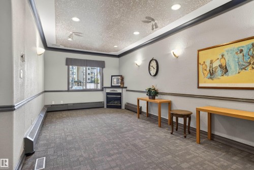 Spacious common area featuring textured walls with dark trim, recessed lighting, and wall sconces - 110 2903 Rabbit Hill Road, Edmonton, AB - Indoor Photo Showing Other Room