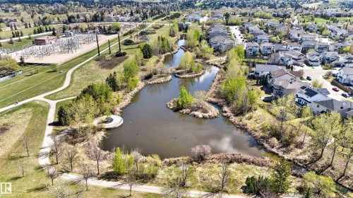 Lakeside community featuring properties with diverse architectural styles, mature trees, and paved walking paths - 110 2903 Rabbit Hill Road, Edmonton, AB - Outdoor With Body Of Water With View