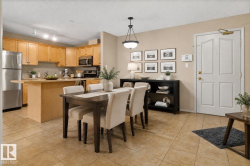 Open-concept living space featuring a kitchen with light wood cabinetry and stainless steel appliances, a breakfast bar, and tile flooring - 110 2903 Rabbit Hill Road, Edmonton, AB - Indoor