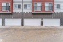 Exterior facade featuring horizontal siding in red and grey tones, multiple white paneled garage doors, and balconies with black railings - 3340 15A Avenue, Edmonton, AB  -  With Exterior 