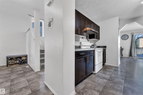 Kitchen with white electric range, a textured ceiling, light countertops, under cabinet range hood, and dark tile patterned flooring - 6152 13 Avenue, Edmonton, AB - Indoor Photo Showing Kitchen