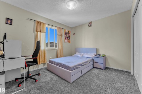 Bedroom with carpet flooring, a closet, a textured ceiling, and an office area - 6152 13 Avenue, Edmonton, AB - Indoor Photo Showing Bedroom