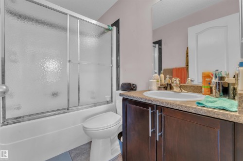 Bathroom with light tile patterned floors, vanity, enclosed tub / shower combo, and a textured ceiling - 6152 13 Avenue, Edmonton, AB - Indoor Photo Showing Bathroom