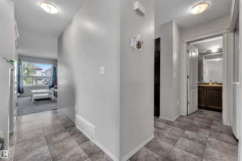 Hall featuring a textured ceiling and light tile patterned floors - 6152 13 Avenue, Edmonton, AB - Indoor Photo Showing Other Room