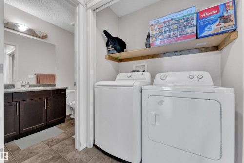 Laundry area with washing machine and clothes dryer, a textured ceiling, and light tile patterned floors - 6152 13 Avenue, Edmonton, AB - Indoor Photo Showing Laundry Room