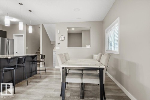 Open-concept living space featuring wood-finish flooring, a kitchen island with stone countertop, stainless steel appliances, a dining area, and a window with blinds - 236 39 Avenue, Edmonton, AB - Indoor Photo Showing Dining Room