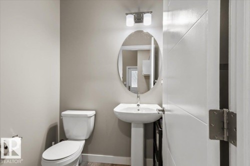 Pedestal sink with chrome faucet, oval mirror, and contemporary two-light vanity fixture - 236 39 Avenue, Edmonton, AB - Indoor Photo Showing Bathroom