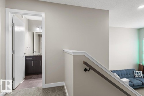 Hallway with carpeted flooring leading to a bathroom featuring a dark wood vanity with a light-colored countertop - 236 39 Avenue, Edmonton, AB - Indoor Photo Showing Other Room