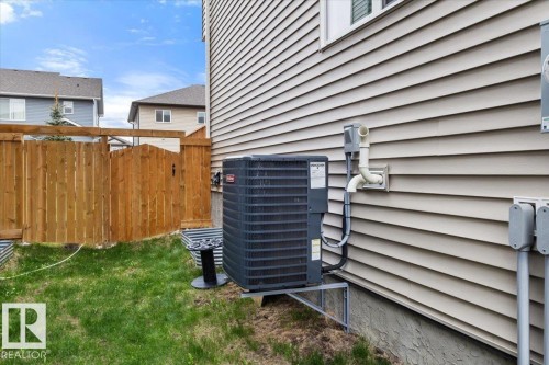 Beige horizontal siding exterior with a dark-colored HVAC unit and a natural wood privacy fence - 236 39 Avenue, Edmonton, AB - Outdoor