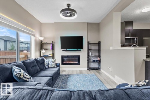 Living area featuring a modern electric fireplace, wall-mounted television, and wood-finish flooring - 236 39 Avenue, Edmonton, AB - Indoor Photo Showing Living Room With Fireplace