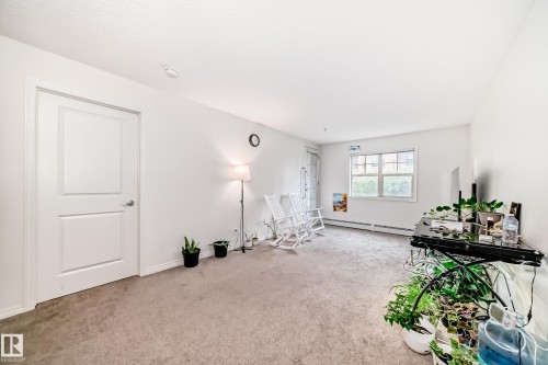 Carpeted room featuring white walls, a white paneled door, a window with white trim, and a glass-paned door - 113 11441 Ellerslie Road, Edmonton, AB - Indoor Photo Showing Other Room