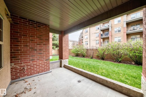 Covered patio featuring a concrete slab floor, brick wall, and soffit ceiling - 113 11441 Ellerslie Road, Edmonton, AB - Outdoor