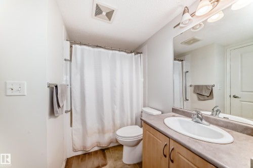 Bathroom featuring a single vanity with a laminate countertop, undermount sink, and chrome faucet - 113 11441 Ellerslie Road, Edmonton, AB - Indoor Photo Showing Bathroom