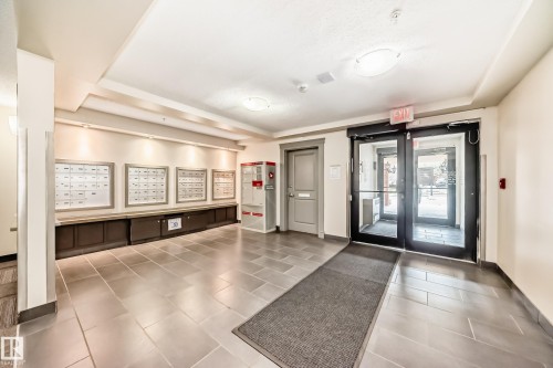 Lobby featuring large format tile flooring, built-in mailboxes with recessed lighting, and a neutral color palette - 113 11441 Ellerslie Road, Edmonton, AB - Indoor Photo Showing Other Room